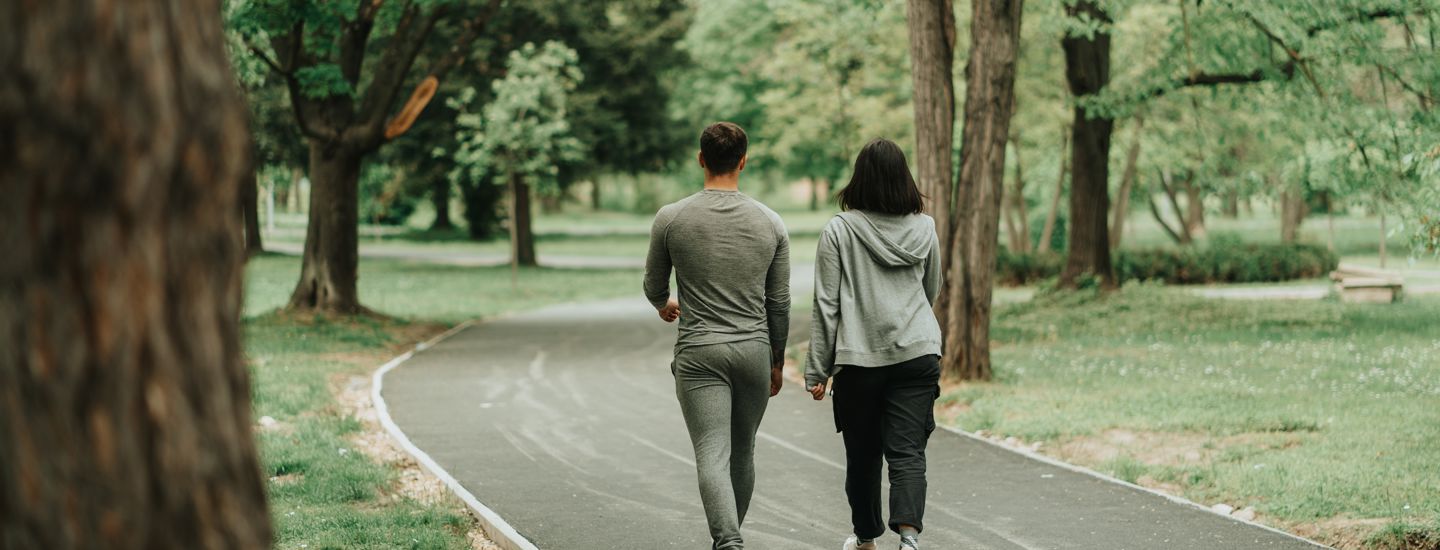 Par som promenerar längs en asfalterad väg i en park