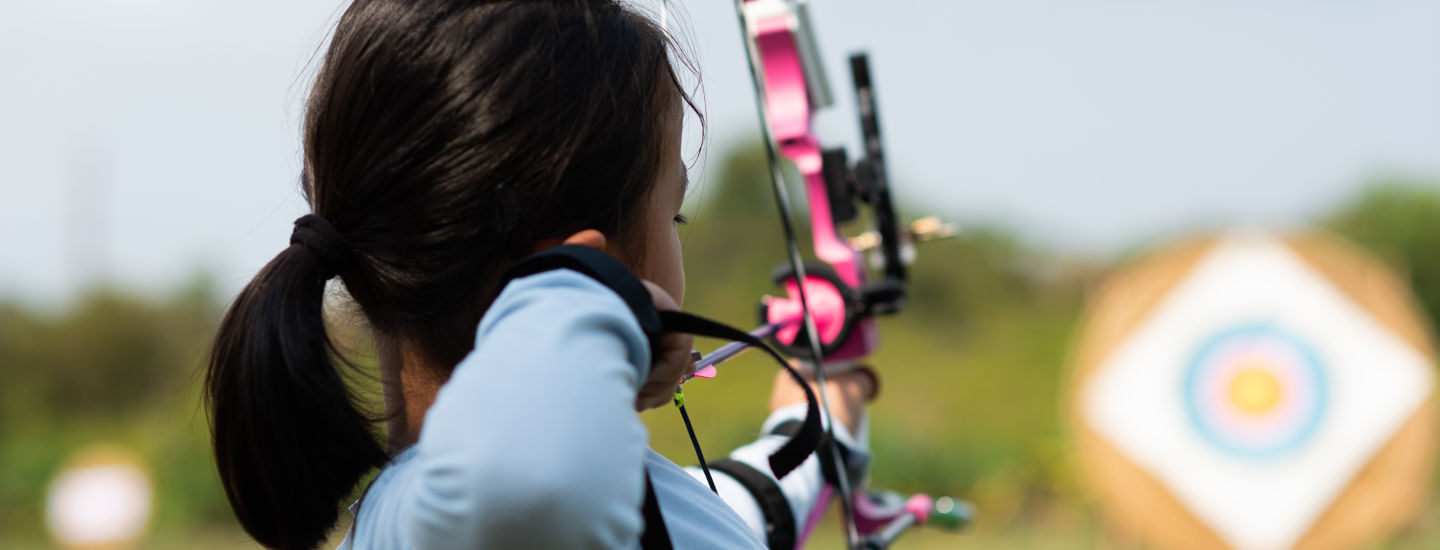 Flick skjuter en rosa pilbåge mot en tavla