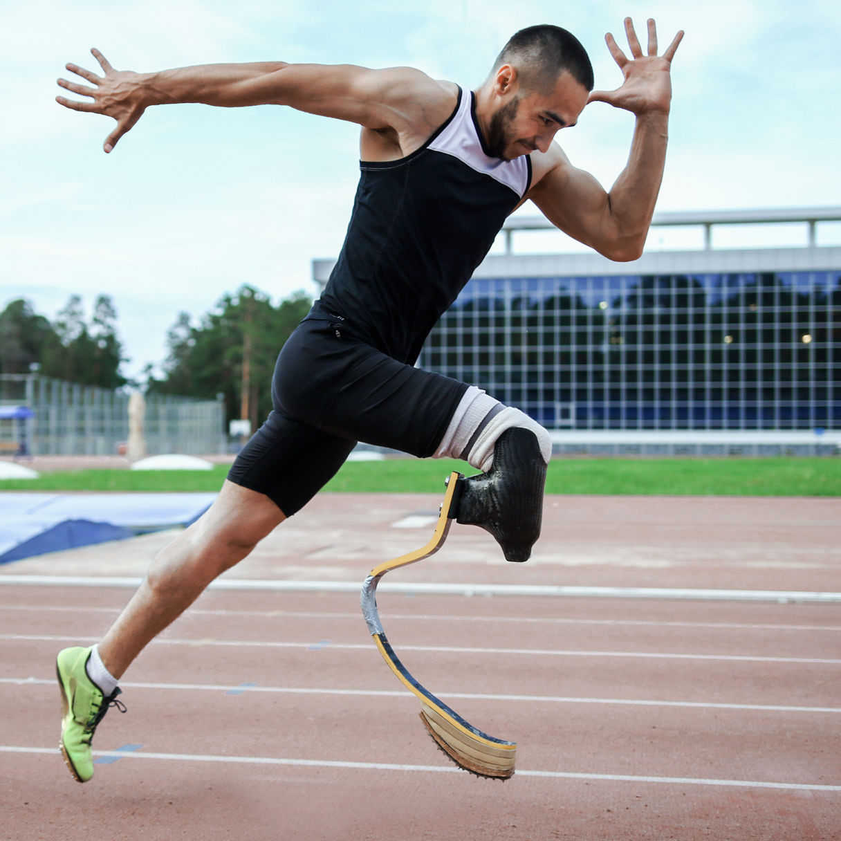 Man med benprotes springer på löparbana