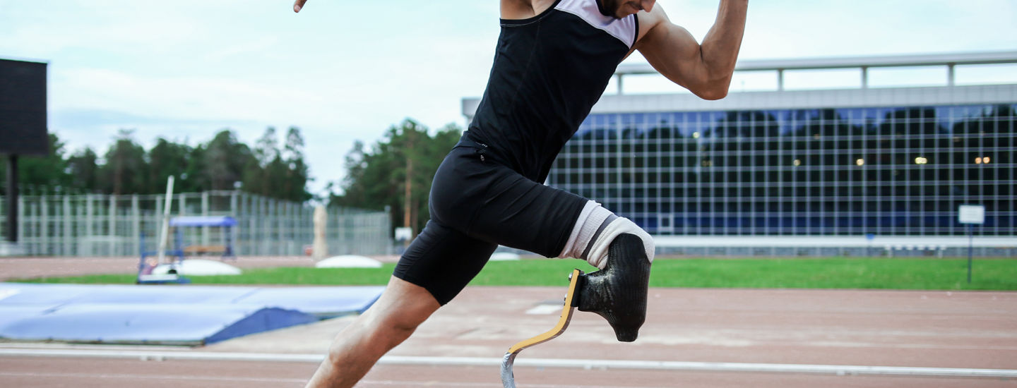 Man med benprotes springer på löparbana