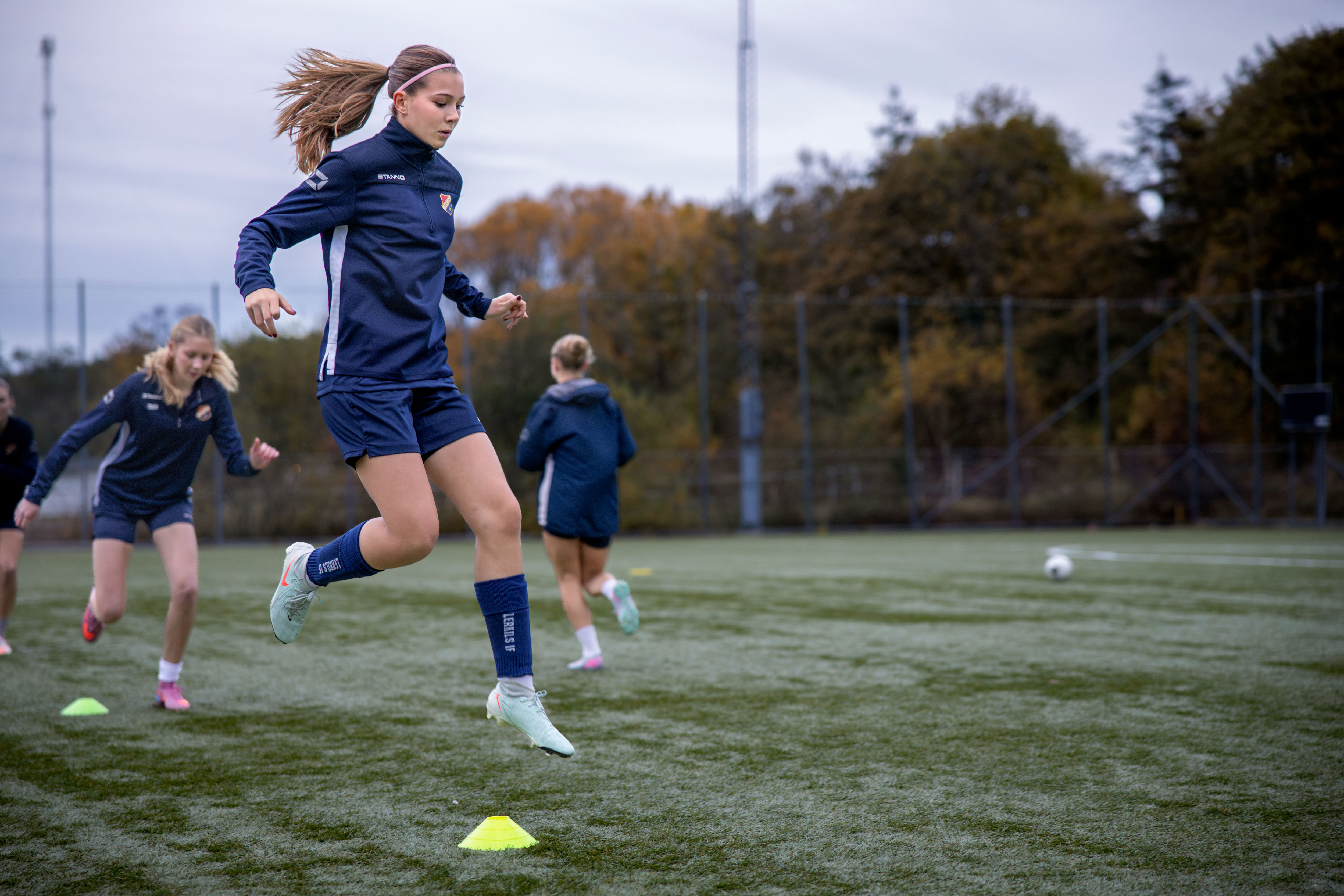Lerkils damfotbollslag värmer upp och tjej hoppar 