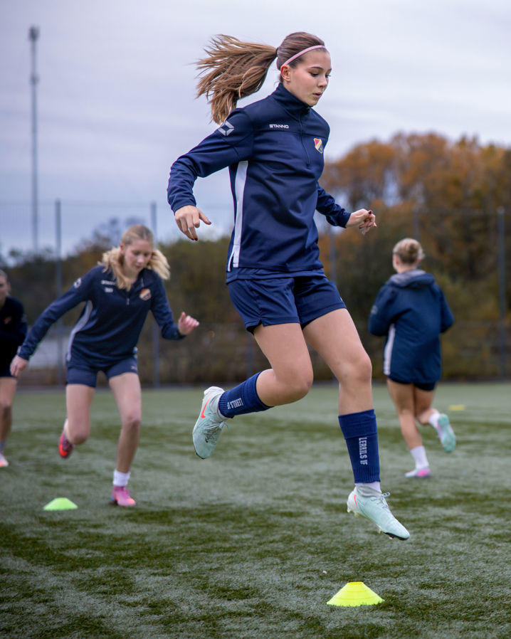 Lerkils damfotbollslag värmer upp och tjej hoppar