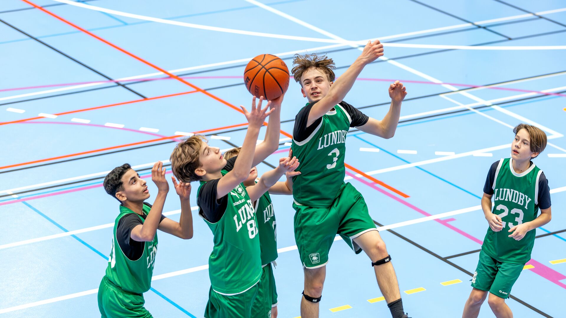 Pojkar spelar basket och kämpar om bollen