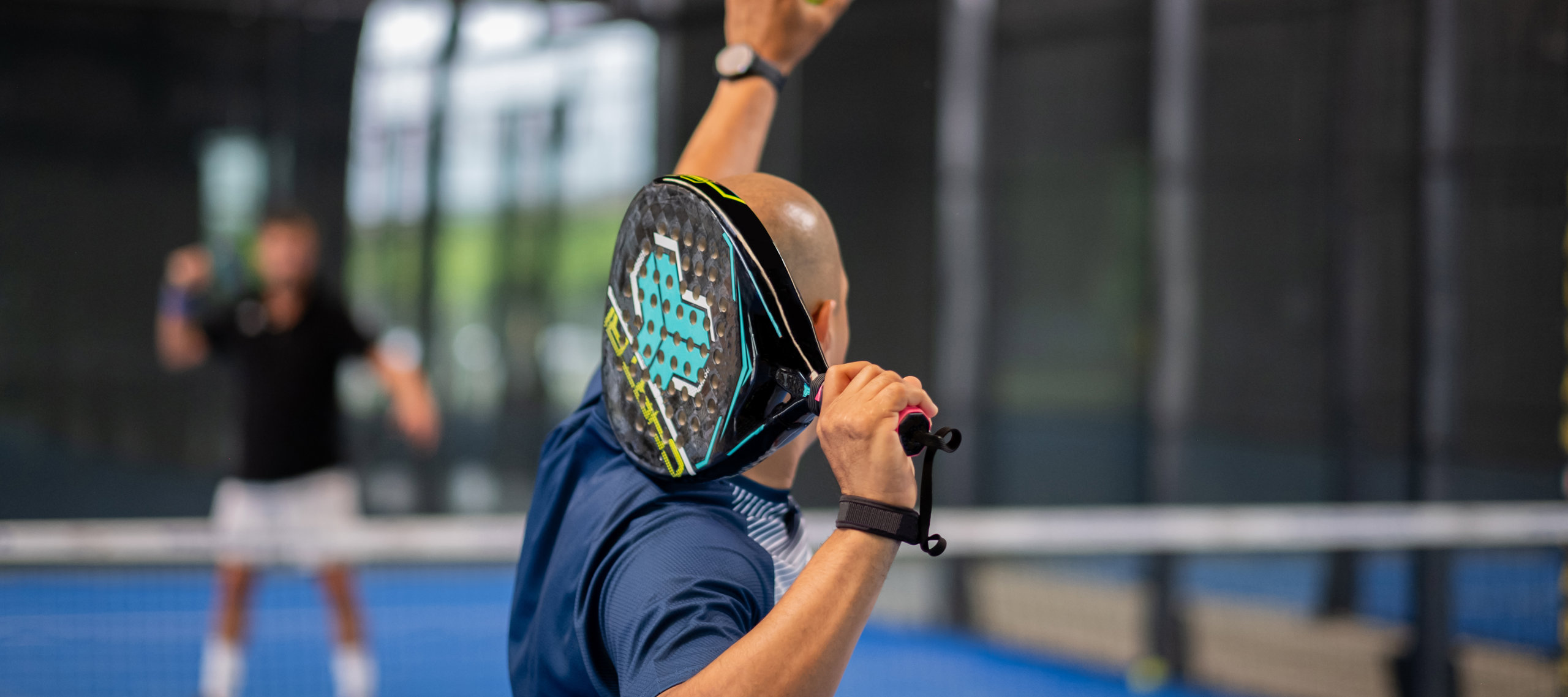 En man gör sig redo för att serva på en padelbana