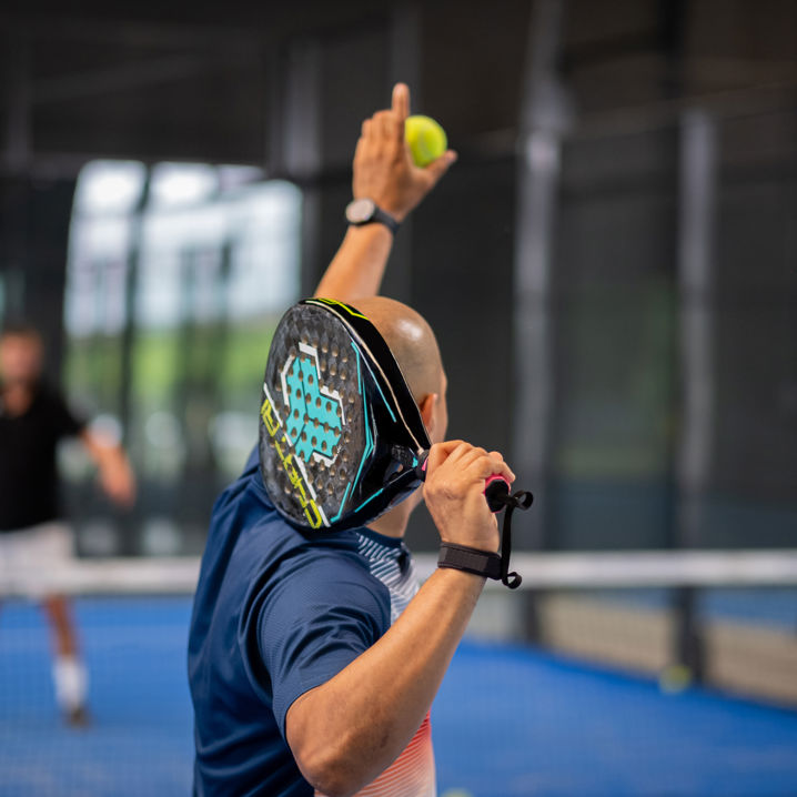 En man gör sig redo för att serva på en padelbana