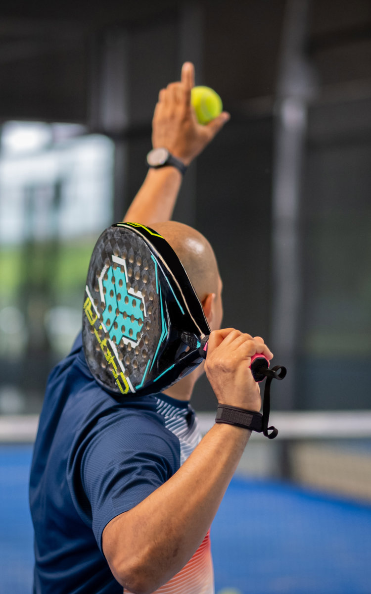 En man gör sig redo för att serva på en padelbana