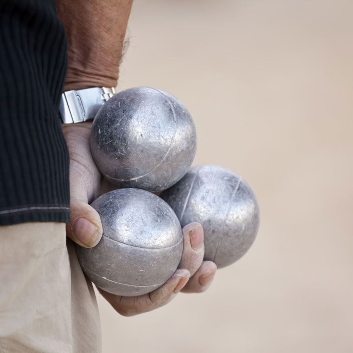 En hand som håller i tre bouleklot intill sidan av kroppen