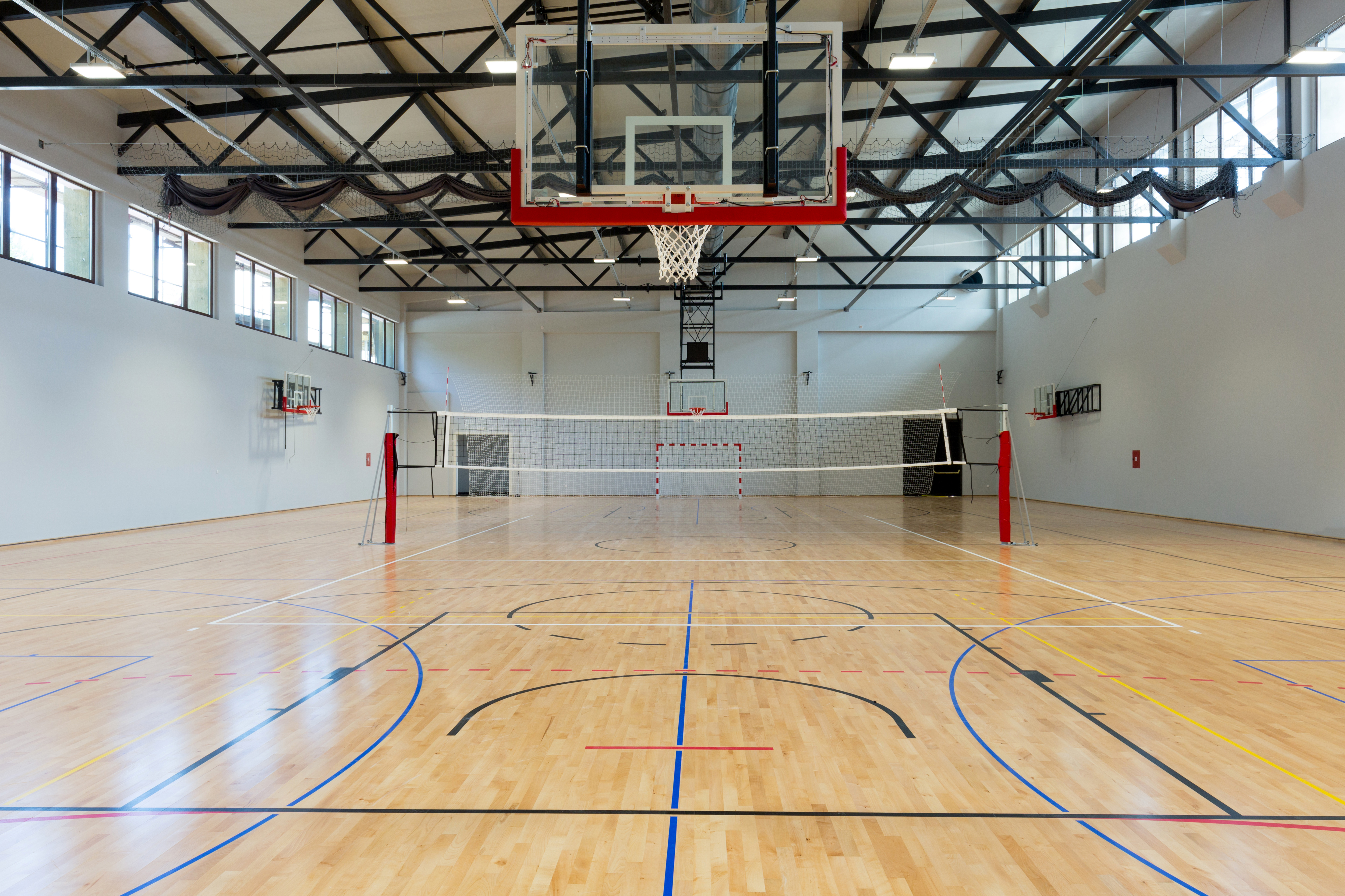 En tom idrottshallar med basketkorgar och volleybollnät