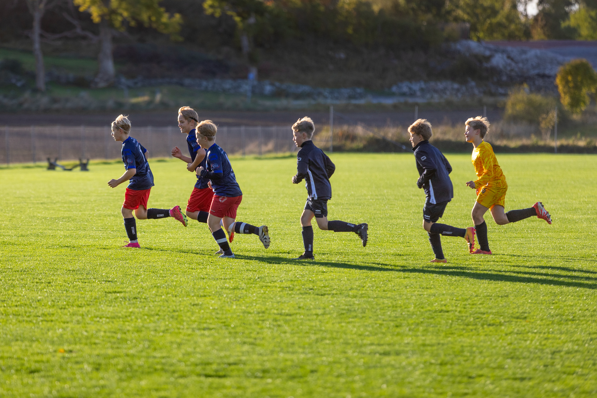 Pojkar från Lerkil springer på en fotbollsplan och värmer upp