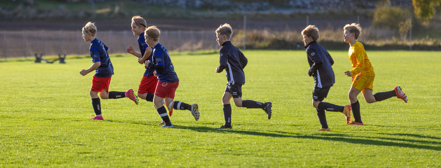 Pojkar från Lerkil springer på en fotbollsplan och värmer upp