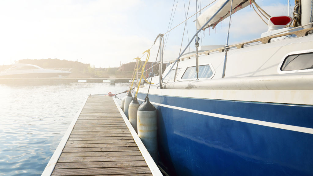 En blå och vit segelbåt som lagt till vid en brygga