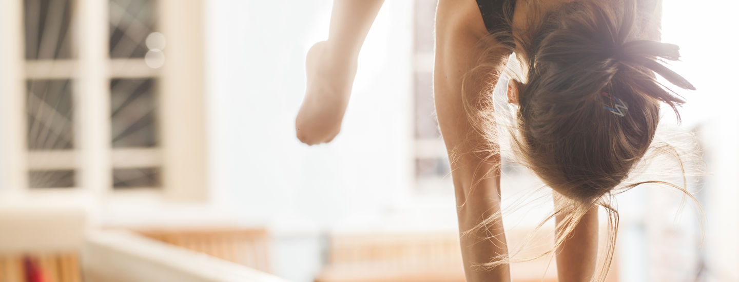 Flicka som tränar gymnastik handstående på en bom