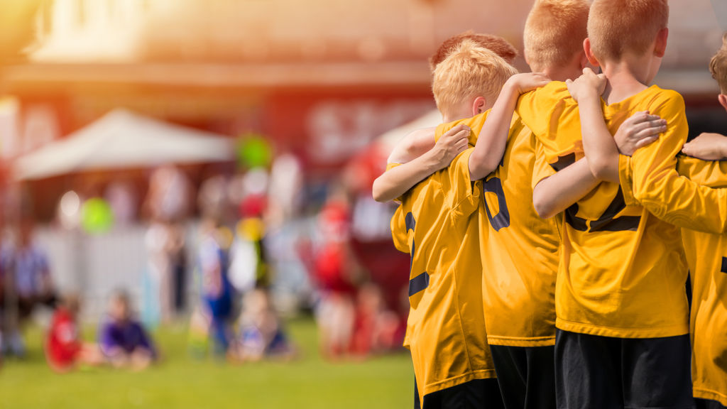 Ett pojklag klädda i ett gul-svart matchställ med armarna runt varandra