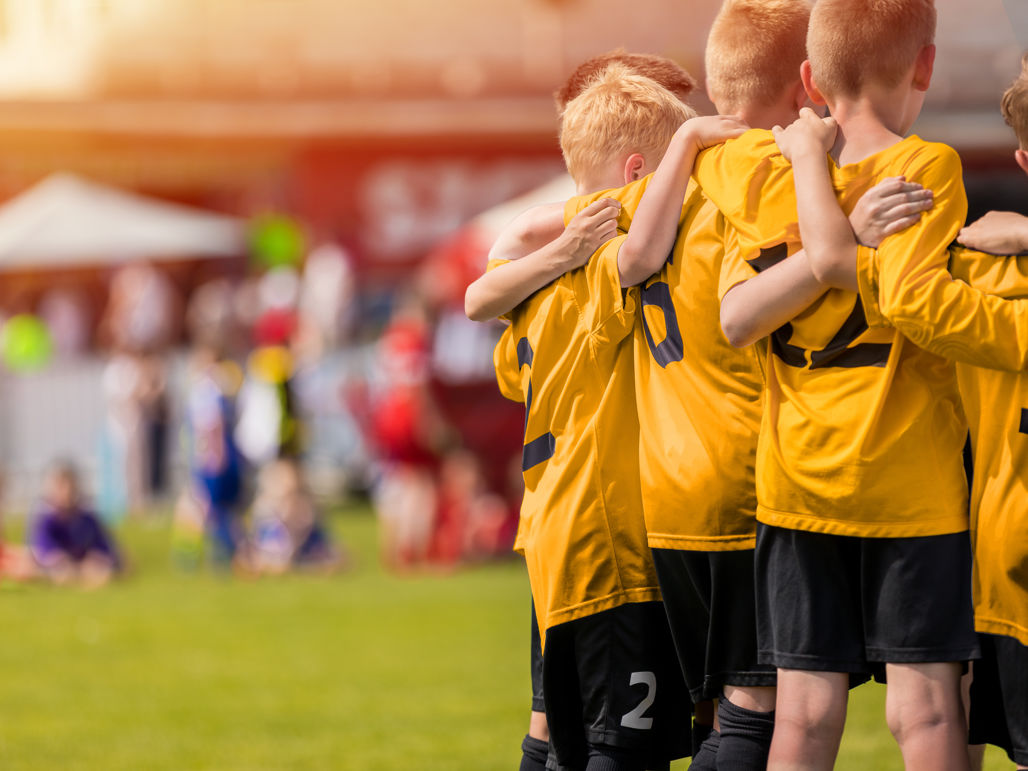 Ett pojklag klädda i ett gul-svart matchställ med armarna runt varandra