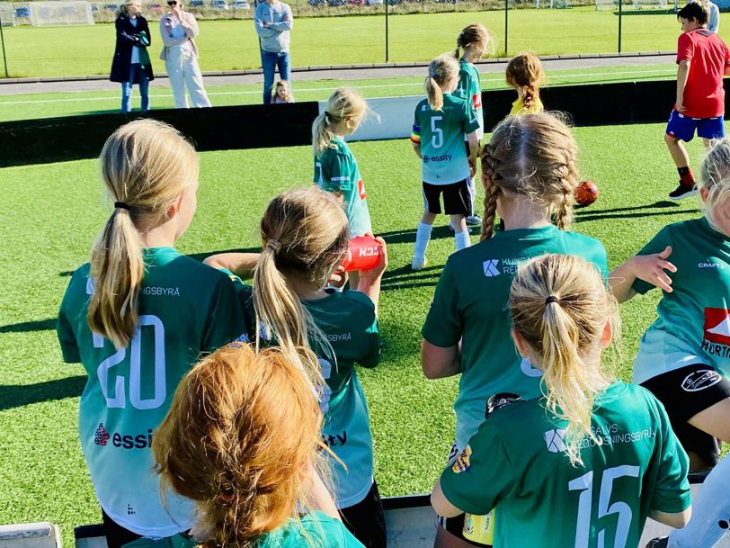 flickor i gröna fotbollströjor spelar fotboll på fotbollsplan