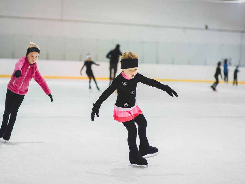 Flickor åker konståkning i en ishall