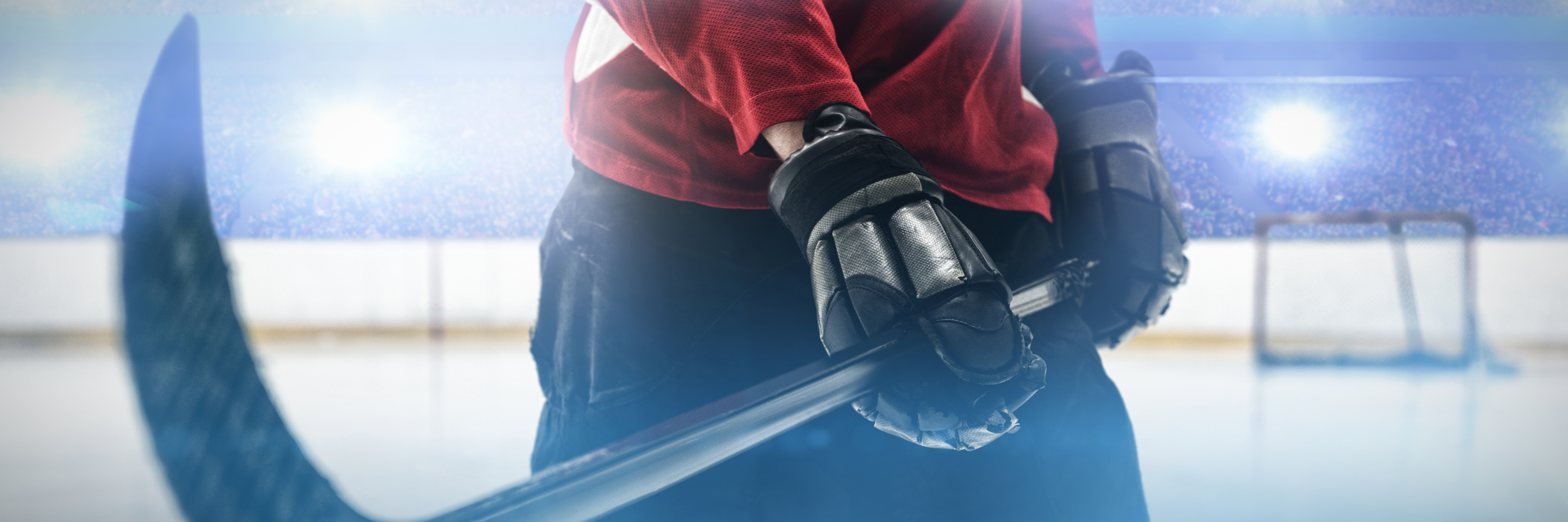 En hockeyspelare som håller en hockeyklubba i en upplyst ishall