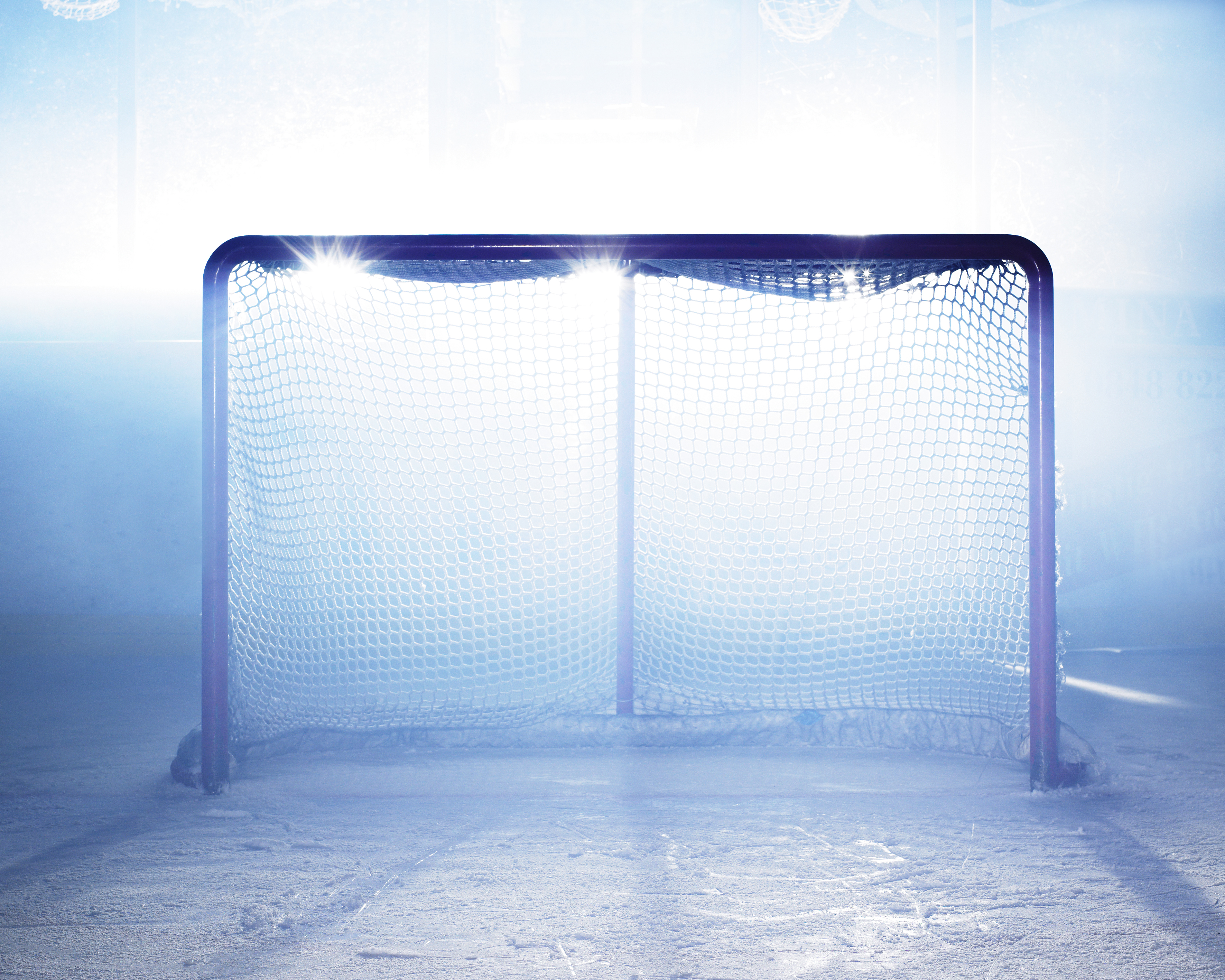 Ett hockeymål i en ishall som lyses upp av strålkastare