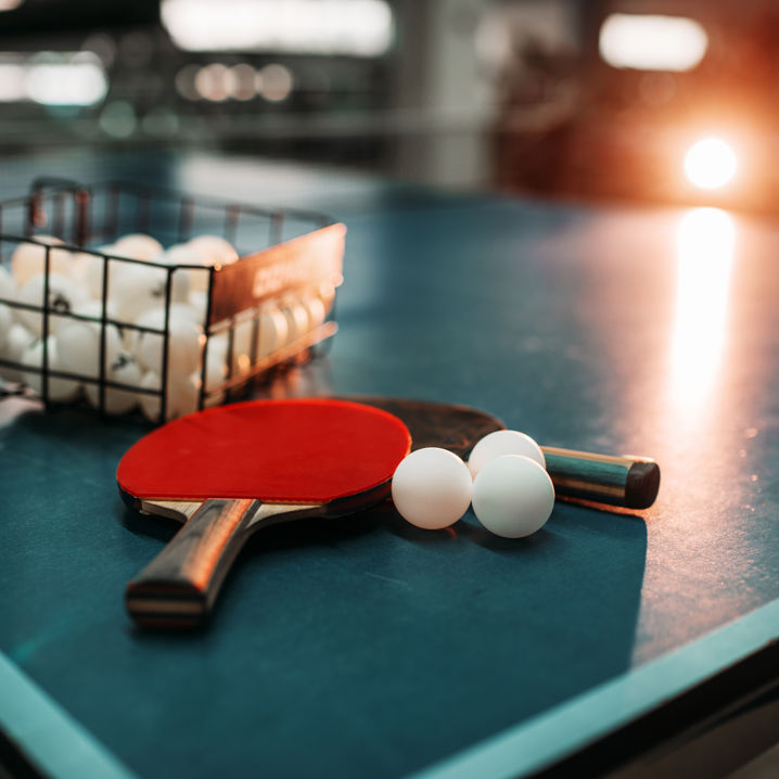 Två bordtennisracket ligger på ett pingisbord tillsammans med en mängd pingisbollar