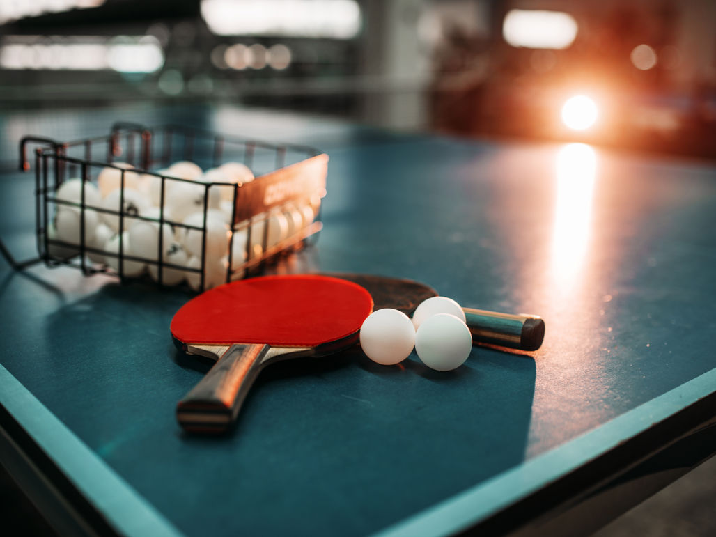 Två bordtennisracket ligger på ett pingisbord tillsammans med en mängd pingisbollar