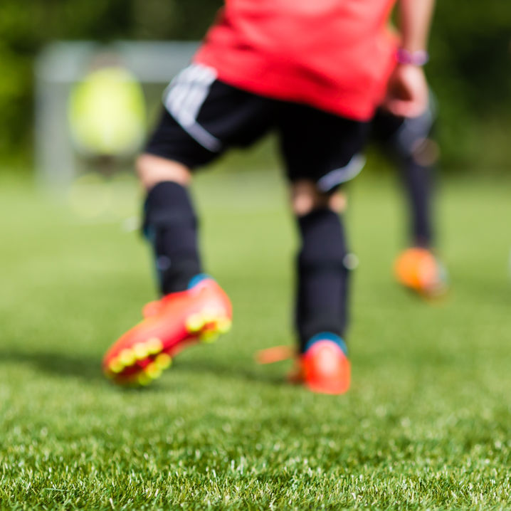 Unga fotbollsspelare tränkar fotboll på en gräsplan