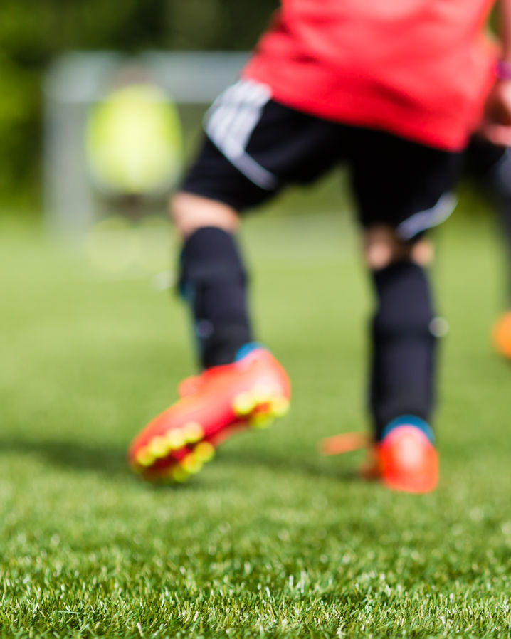 Unga fotbollsspelare tränkar fotboll på en gräsplan