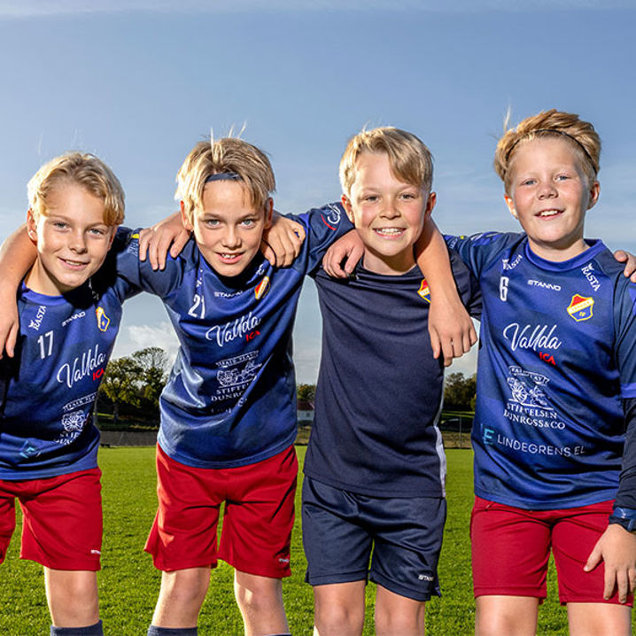 Fotbollskillar i träningskläder håller varandra om axlarna