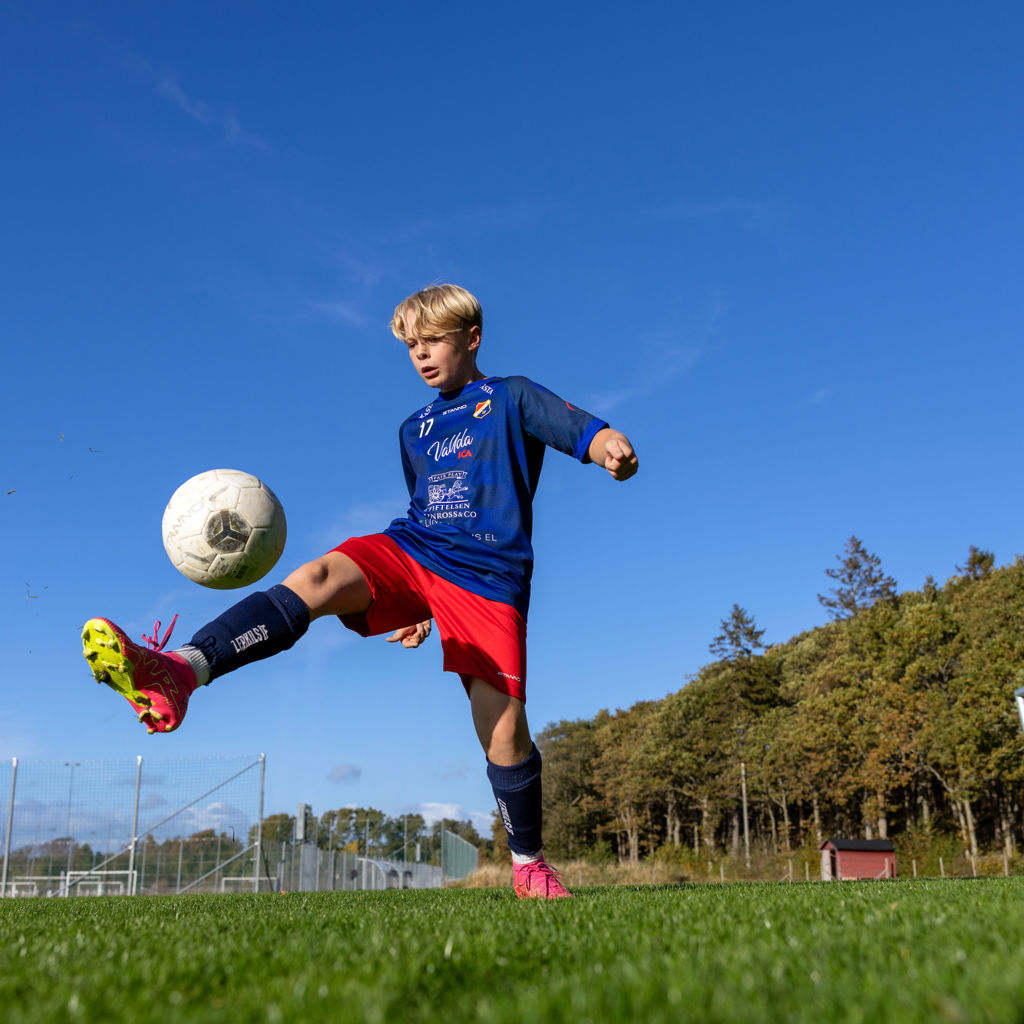 Lerkil fotbollsspelare bollar med fotbollen