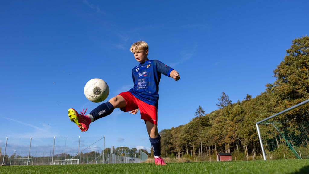 Lerkil fotbollsspelare bollar med fotbollen