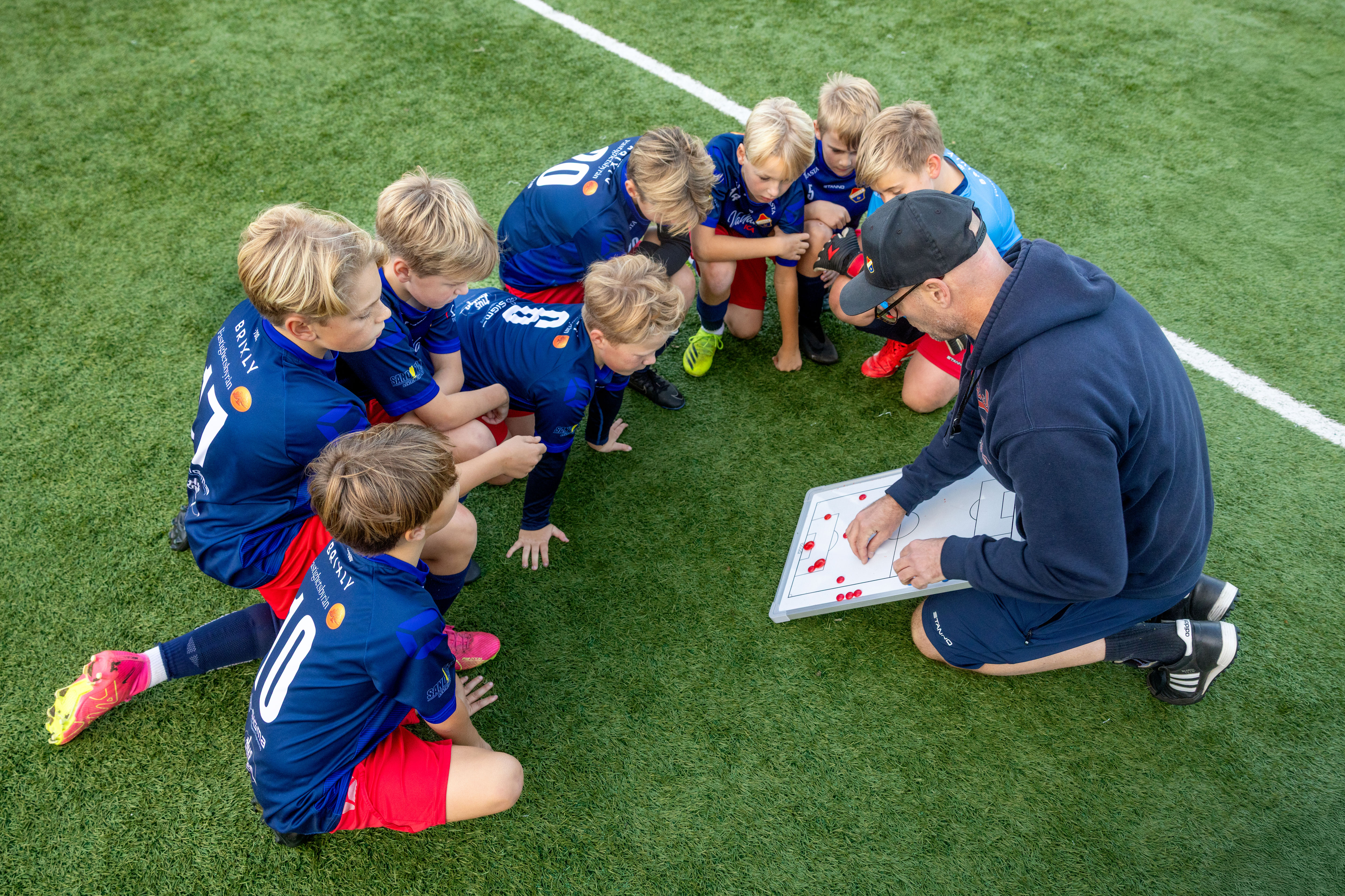 Fotbollslag pojkar Lerkil sitter på gräset och pratar taktik