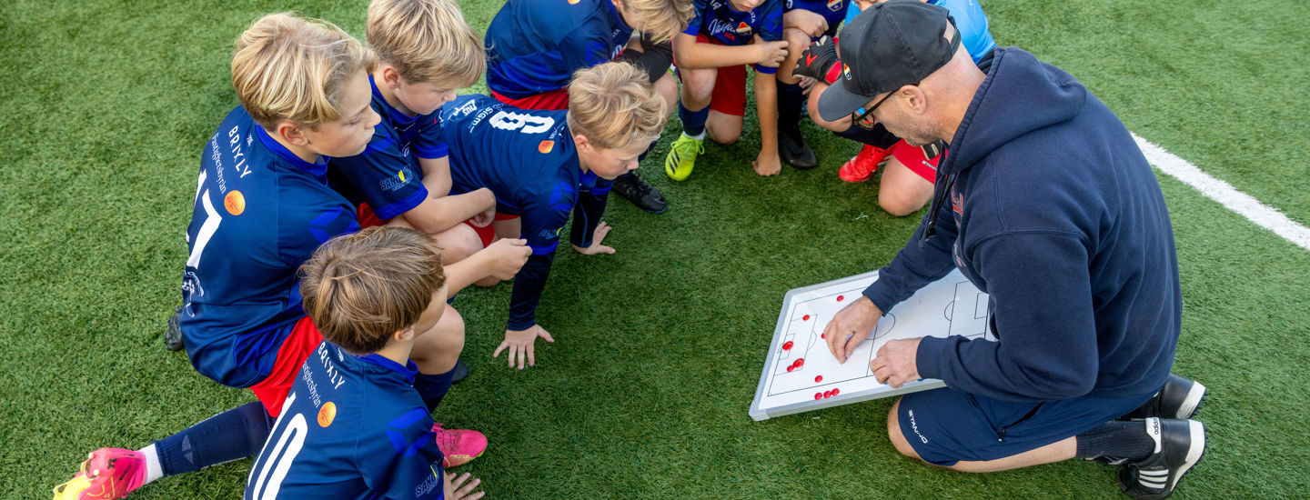 Fotbollslag pojkar Lerkil sitter på gräset och pratar taktik