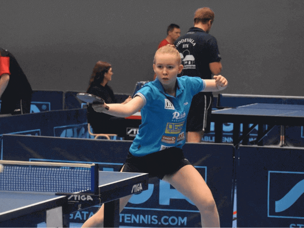 Ung tjej från BTK Rekord spelar en pingismatch under en turnering, omgiven av flera pingisbord