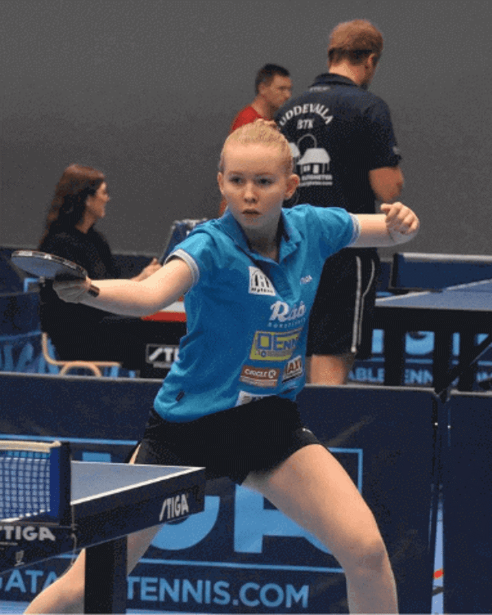 Ung tjej från BTK Rekord spelar en pingismatch under en turnering, omgiven av flera pingisbord