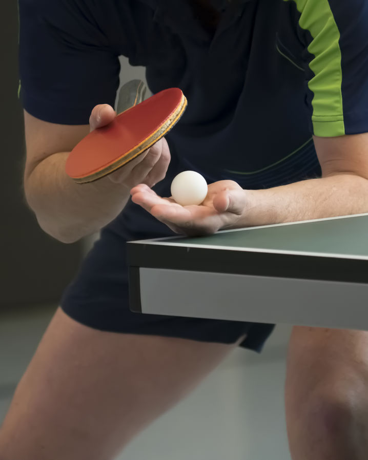 En person står redo för att serva framför ett bordtennisbord
