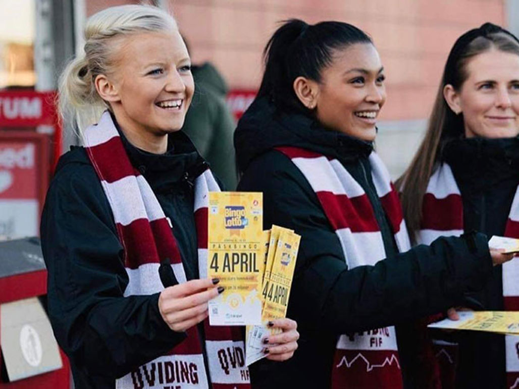 Glada tjejer med rödvit-randiga halsdukar ler och säljer bingolotter till påsk