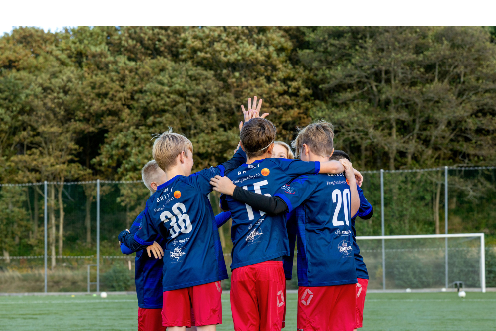 Pojkfotbollslag står på planen, kramas och gör high five