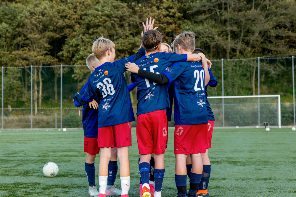 Pojkfotbollslag står på planen, kramas och gör high five