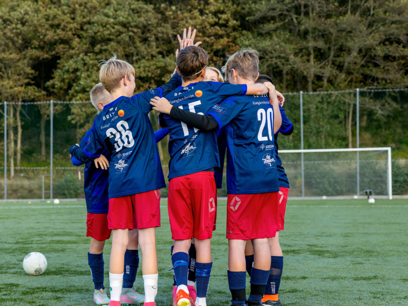 Pojkfotbollslag står på planen, kramas och gör high five