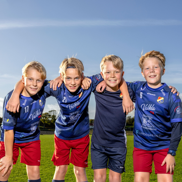 Fyra unga fotbollskillar håller om varandra 