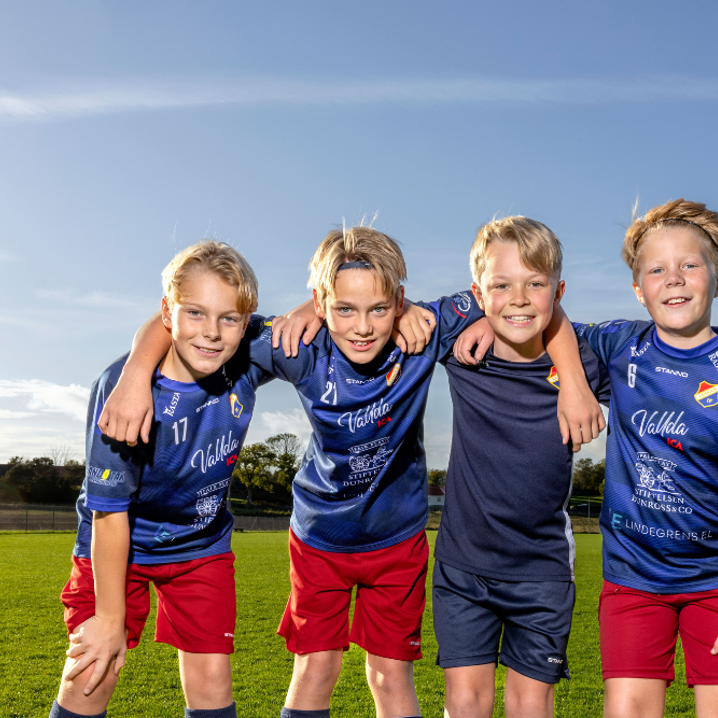 Fyra unga fotbollskillar håller om varandra och ler