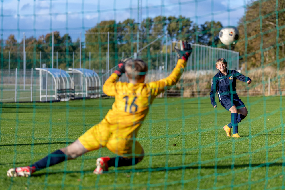 Målvakt i gult matchset slänger sig och försöker rädda ett skott