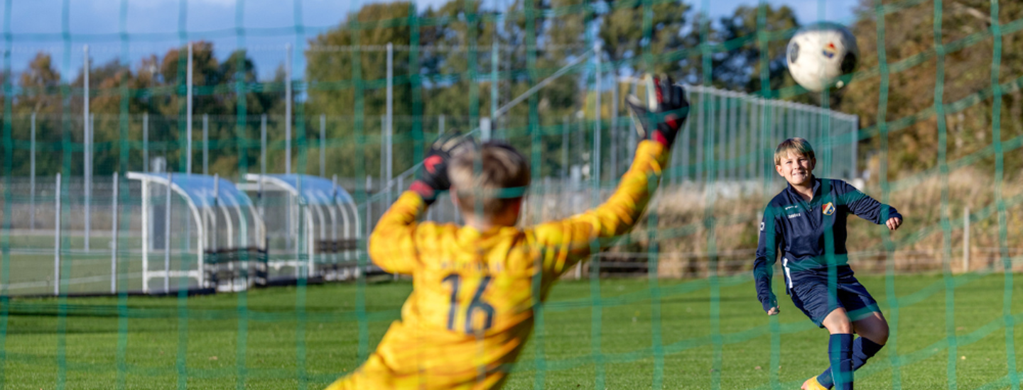 Målvakt i gult matchset slänger sig och försöker rädda ett skott