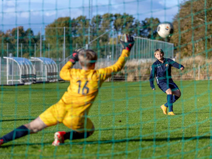 Målvakt i gult matchset slänger sig och försöker rädda ett skott