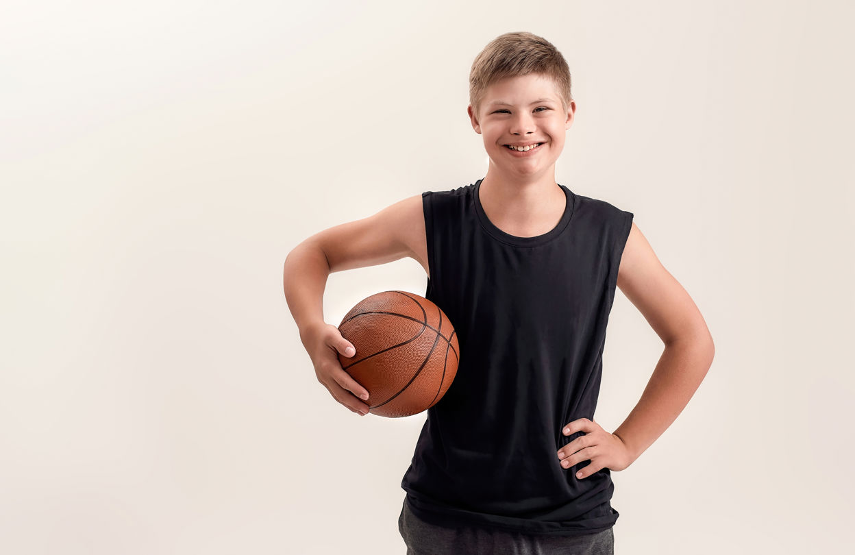 Ung pojke i träningskläder med en basketboll under armen