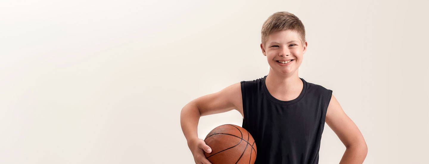 Ung pojke i träningskläder med en basketboll under armen