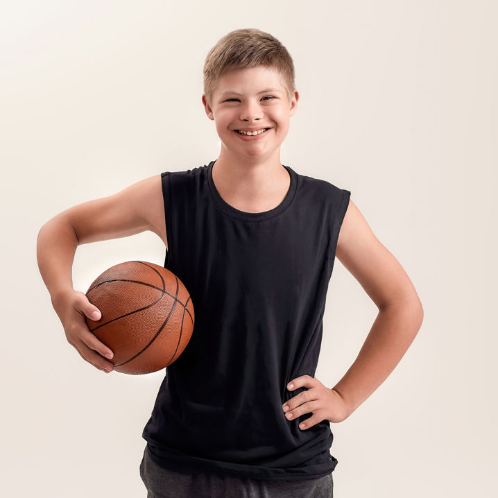 Ung pojke i träningskläder med en basketboll under armen