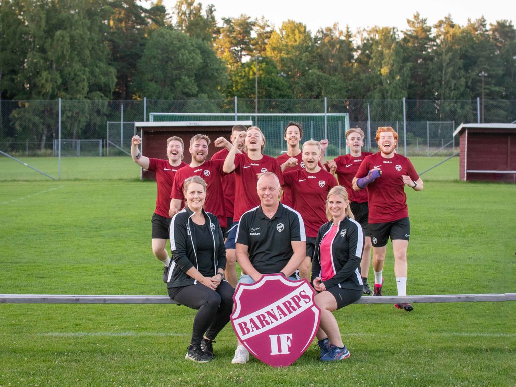 Fotbollslag som håller upp föreningens logotyp utomhus
