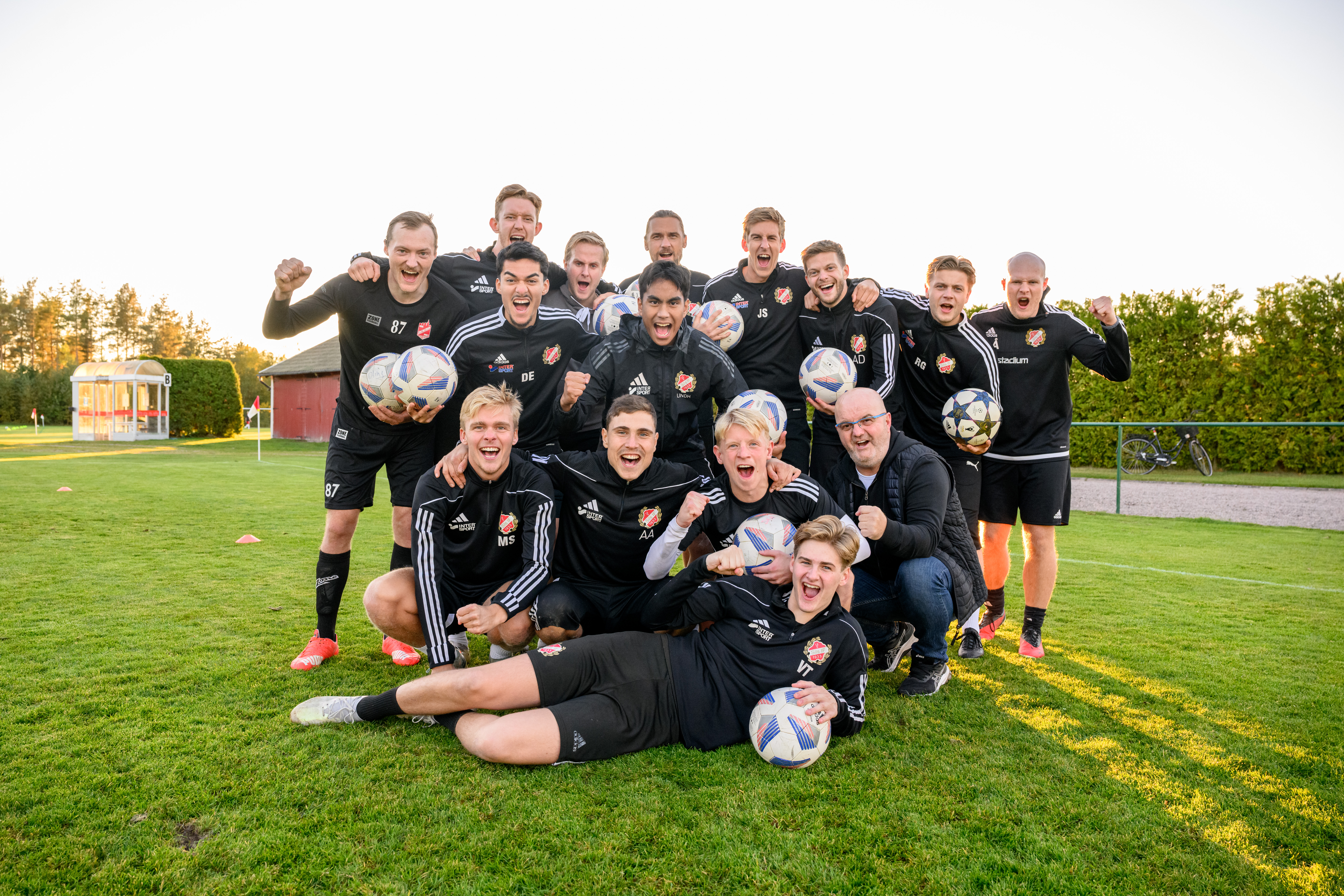 en lagbild på stort fotbollslag som håller upp fotbollar i träningskläder