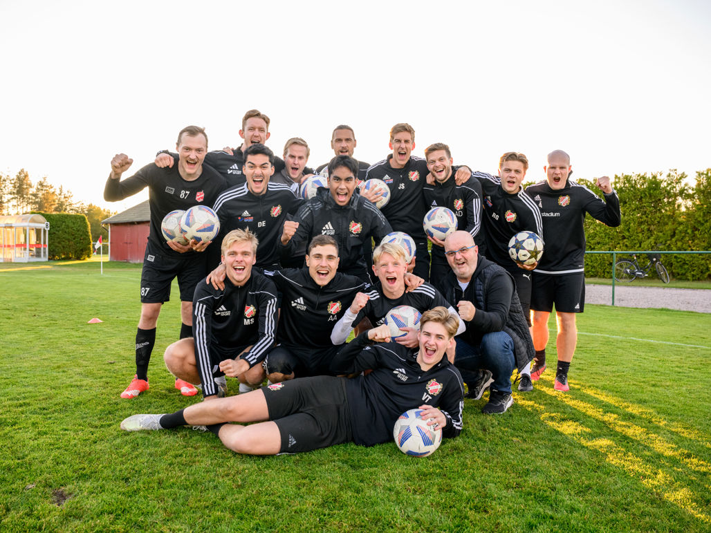 en lagbild på stort fotbollslag som håller upp fotbollar i träningskläder