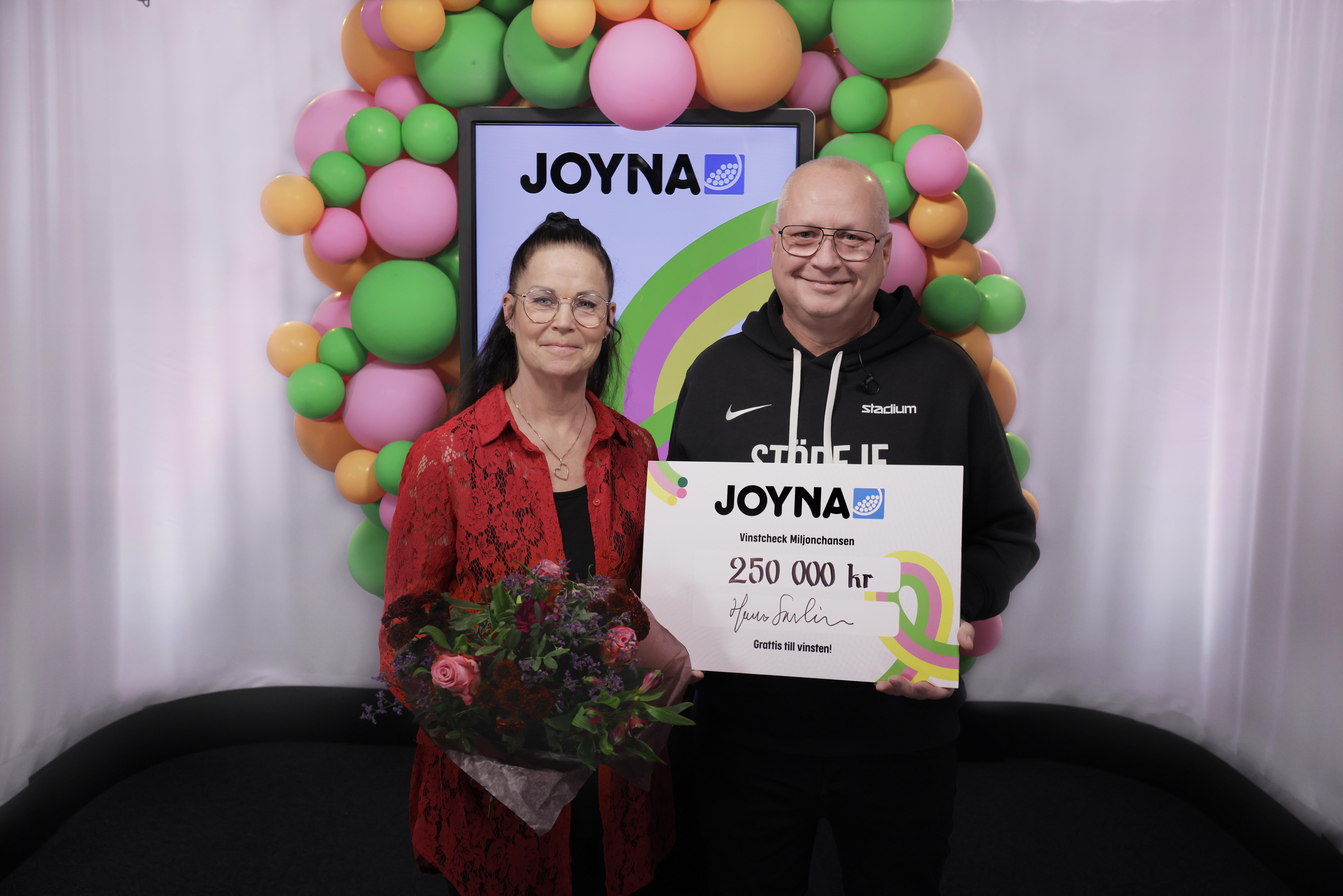 En kvinna och en man som håller i skylt på 250 000 kr